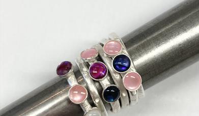 A number of silver rings all stacked together, encrusted with a number of semi precious stones ranging. 