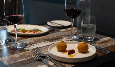 Italian dishes and red wine sit on a restaurant table