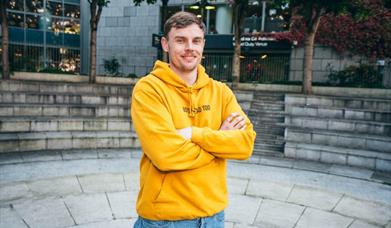 daragh fleming standing with folded arms in a yellow hoodie
