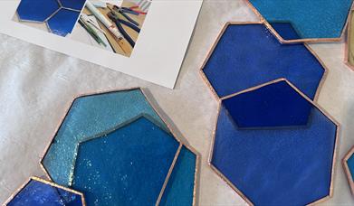 pieces of colourful stained glass in hexagonal shapes, with copper plated edges