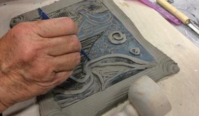clay tile being carefully engraved 