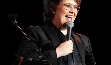 Picture of Emer Maguire laughing holding a microphone.