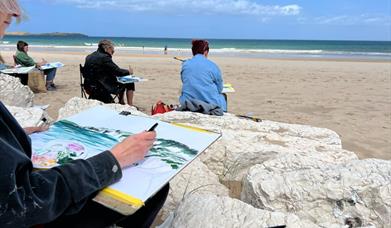 people painting pictures on a beach 