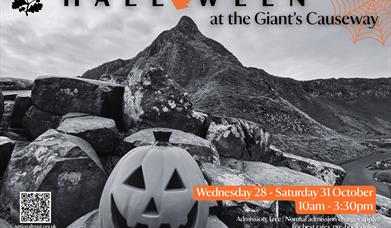 Promotional poster for 'Halloween at the Giant's Causeway' event. Carved pumpkin sitting on top of the Causeway stones, with a dramatic black and whit