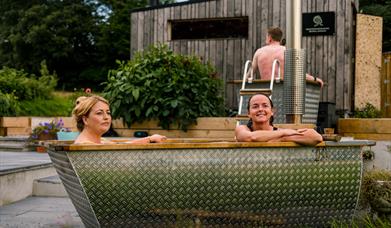 Two ladies relax in an outdoor shared tub