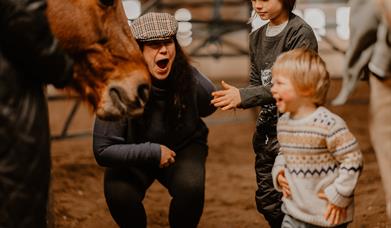 a family laughs and smiles around a horse