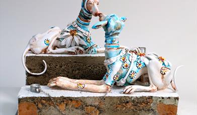 Image of ceramic figures of dogs wearing a blue outfit adorned with daisies