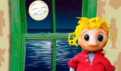 a puppet of a young blonde boy stands before a window with a smiling moon outside