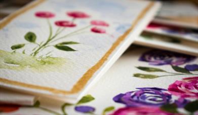 various watercolour pieces by leona devine. the foremost piece depicts a bunch of pink flowers in bloom