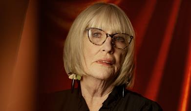 Moyra Donaldson standing in front of a red curtain 