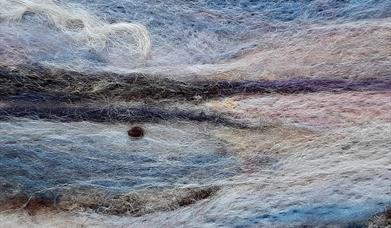 close up of a needle felted representation of a coastal scene