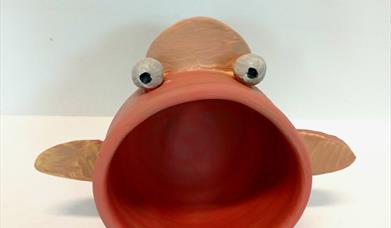 a clay fish with a wide mouth for holding speakers