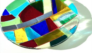 close up image of a mutlticolour glass plate with a pattern of different coloured squares. 