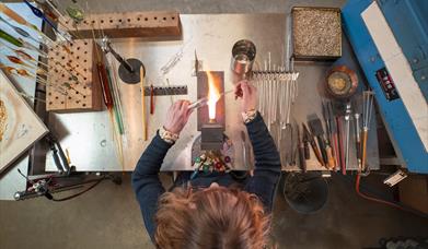 aerial view of a woman working with glass over a flame