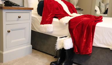 Santa's red suit and boots on a bed at The Causeway Hotel