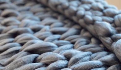 close up photo of a knit-woven throw blanket, highlighting the individual fibers