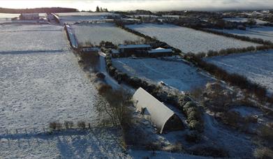 An aerial view of the studio on a Snowy winter day with the snow glistening on the curved roof.