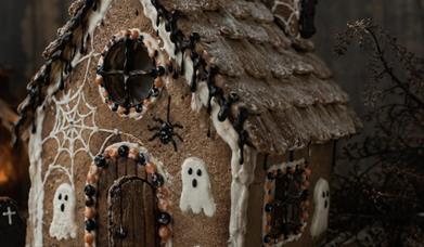 a gingerbread house is decorated with spiders, webs and ghosts for halloween