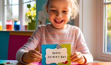 A young girl beams at her handmade father's day card.