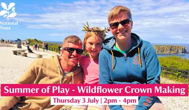 A family pictured enjoying a Wildflower Crown Making session on a sunny day at Carrick-a-Rede