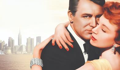 section from movie poster from 'An Affair to Remember' which features a man and woman embracing with the New York City skyline in the distance