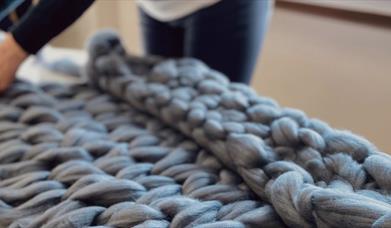 A grey, arm knitted throw 