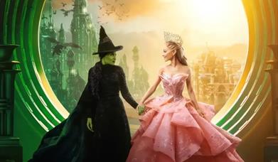 A scene from Wicked with the two main characters Elphaba and Galinda holding hands. 