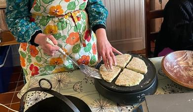 person in a apron bakes bread on a griddle pan