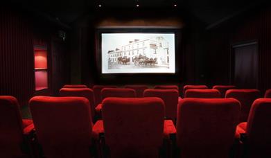 Image shows a movie theatre with red seats