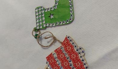 two little wooden christmas decoraitons decorated with paint and sparkly gems 