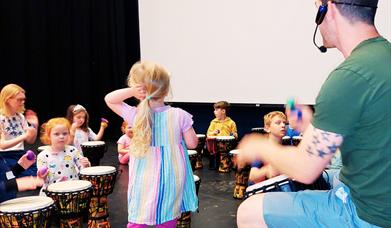 A small class of children being instructed on small drums by James Hamilton.