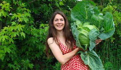 a woman holds a large cabbage