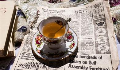 a teacup sitting on top of a newspaper 