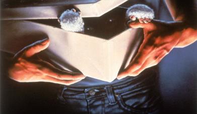 movie poster for Gremlins, featuring a fluffy creature attempting to escape from a box that a man is holding