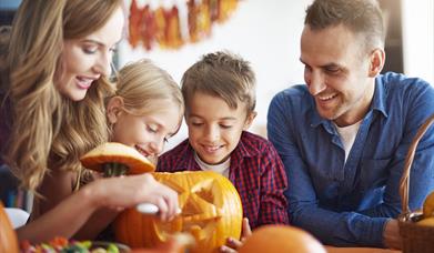 family carving a pumpkin