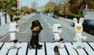 lego figures crossing a road, reminiscent of the famous beatles album cover 