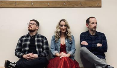 musicians from the band Lore sit on a bench 