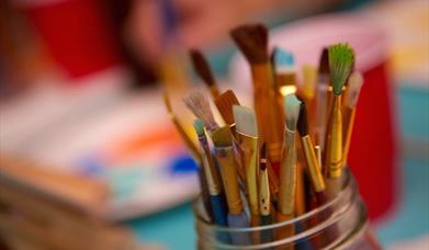 paintbrushes all bunched together in a pot