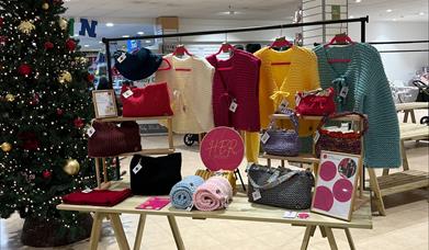 a selection of knitted goods on display beside a christmas tree