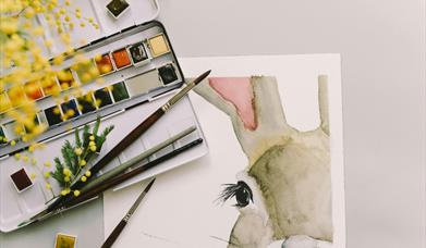 watercolour rabbit painting accompanied by brushes and a palette