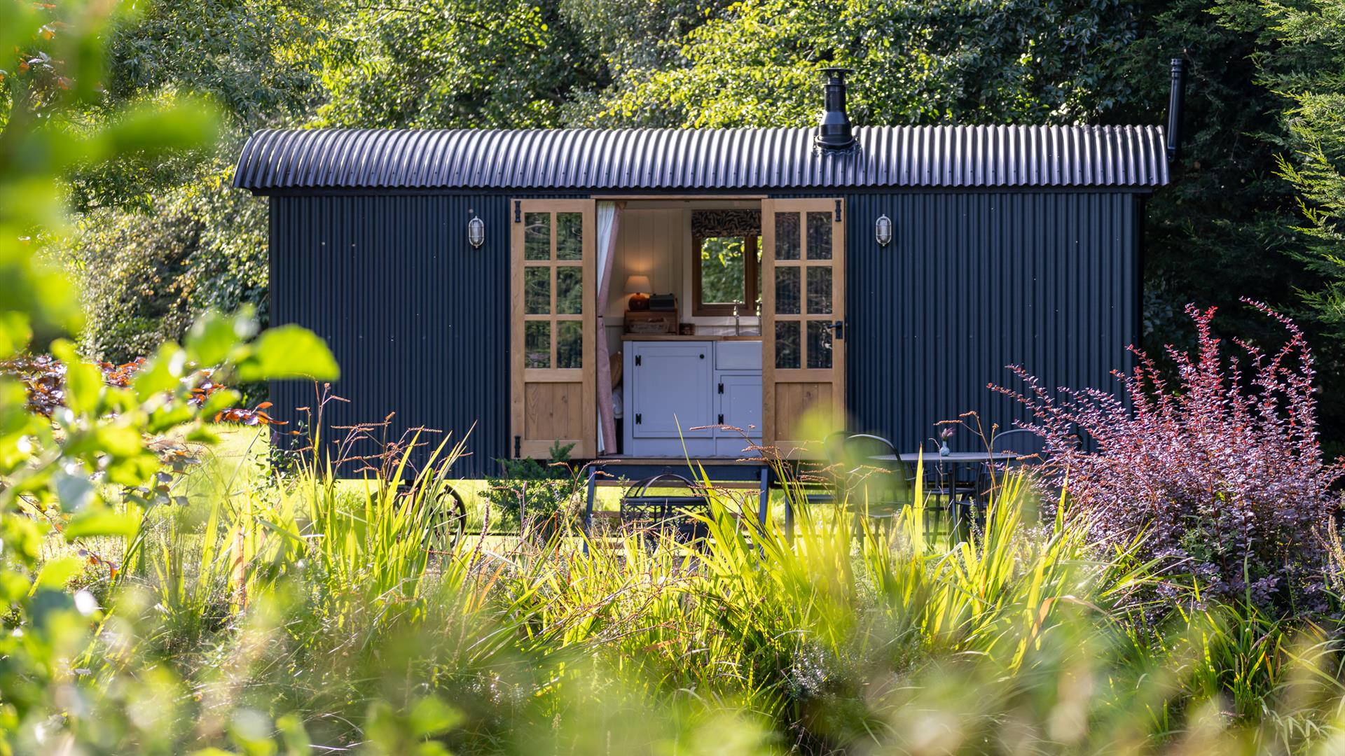 Curlew Hut with pond in foreground and mature trees in background