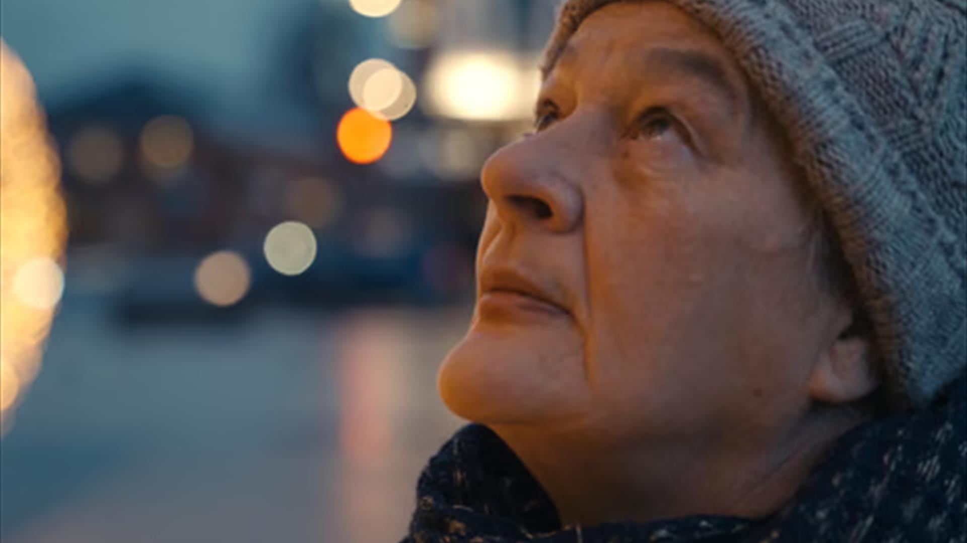 A woman wearing a hat, the city background is blurred.