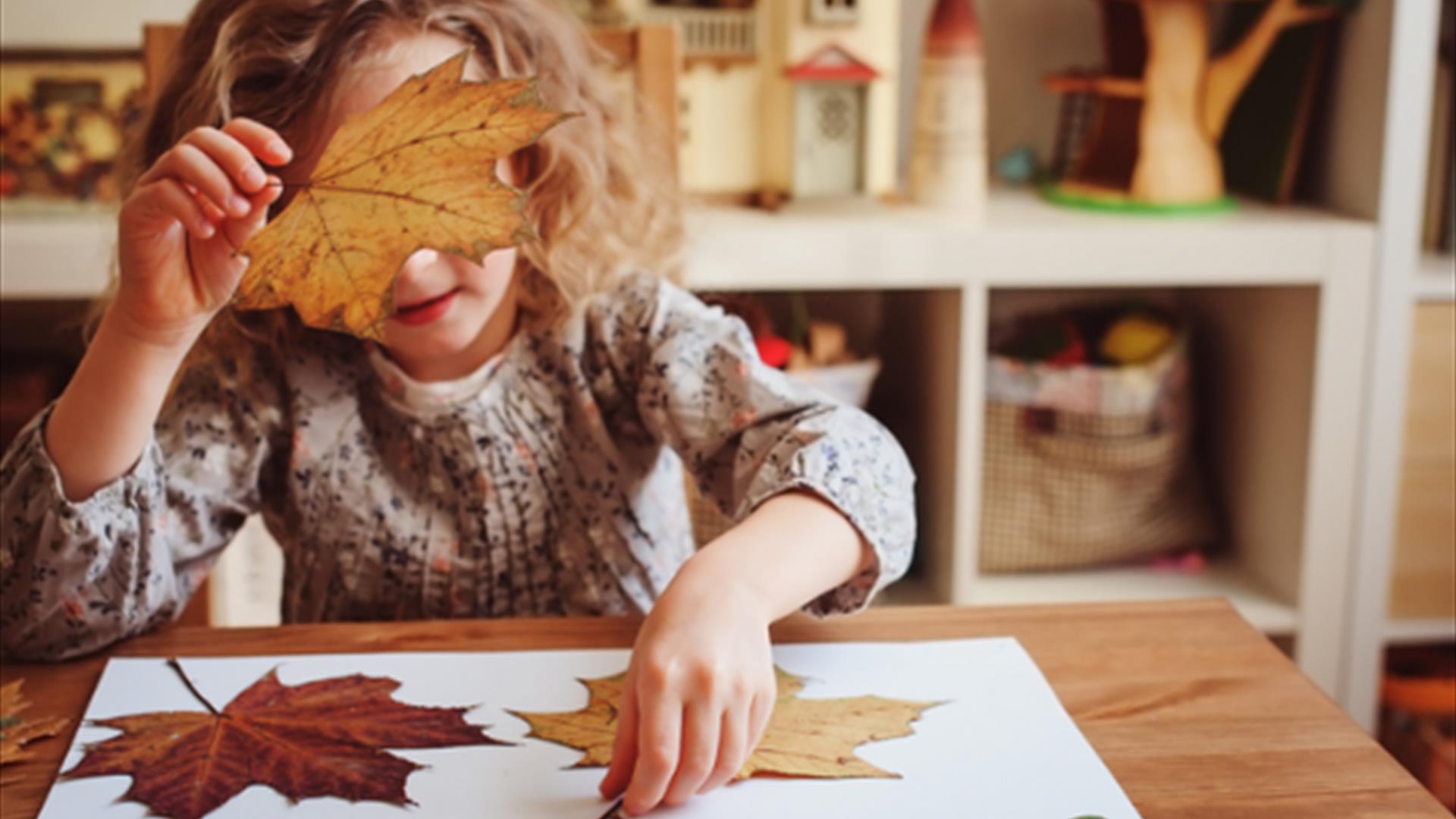little girl taking part in autumn craft with leafs