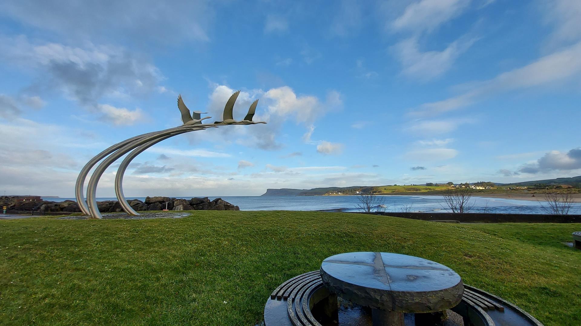 ballycastle sea front, with the swans of lir sculpture in the background