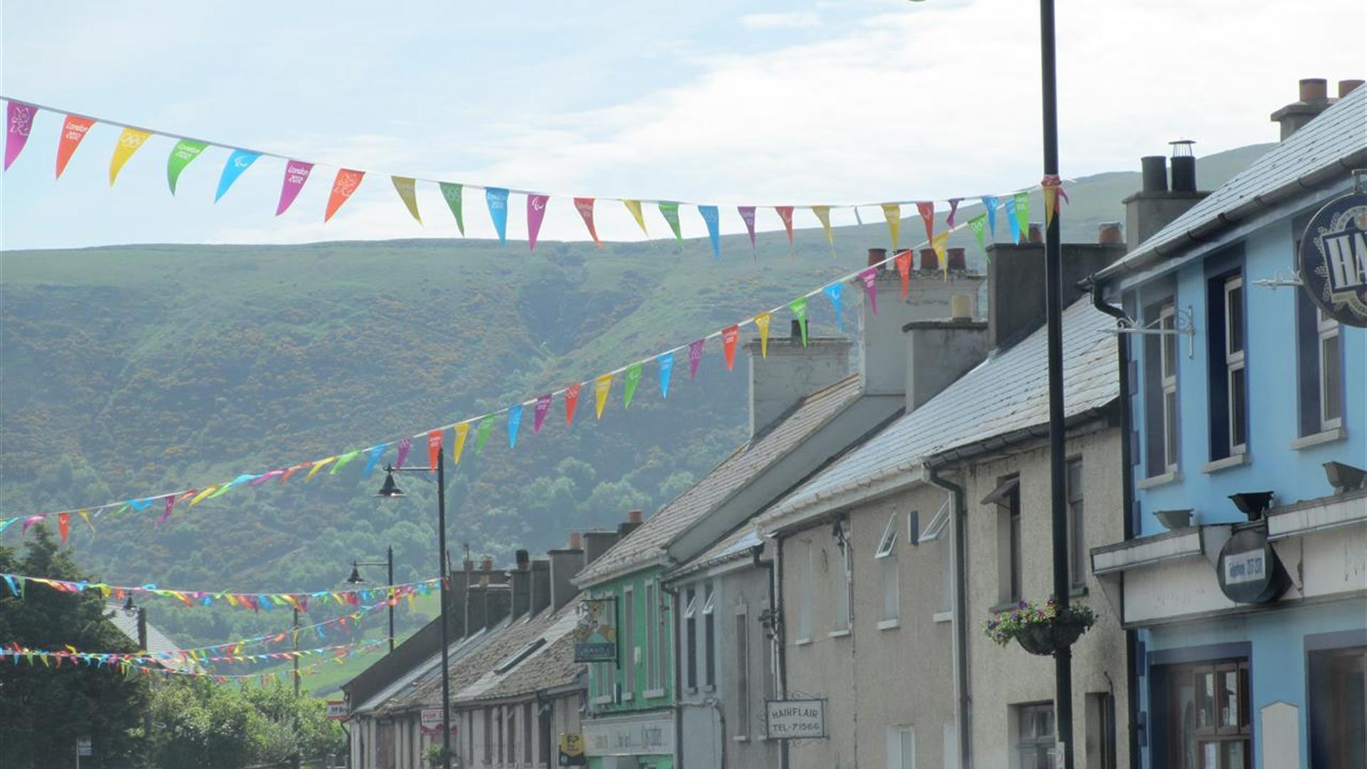 Cushendall street with various coloured flags strung between lamp-posts.