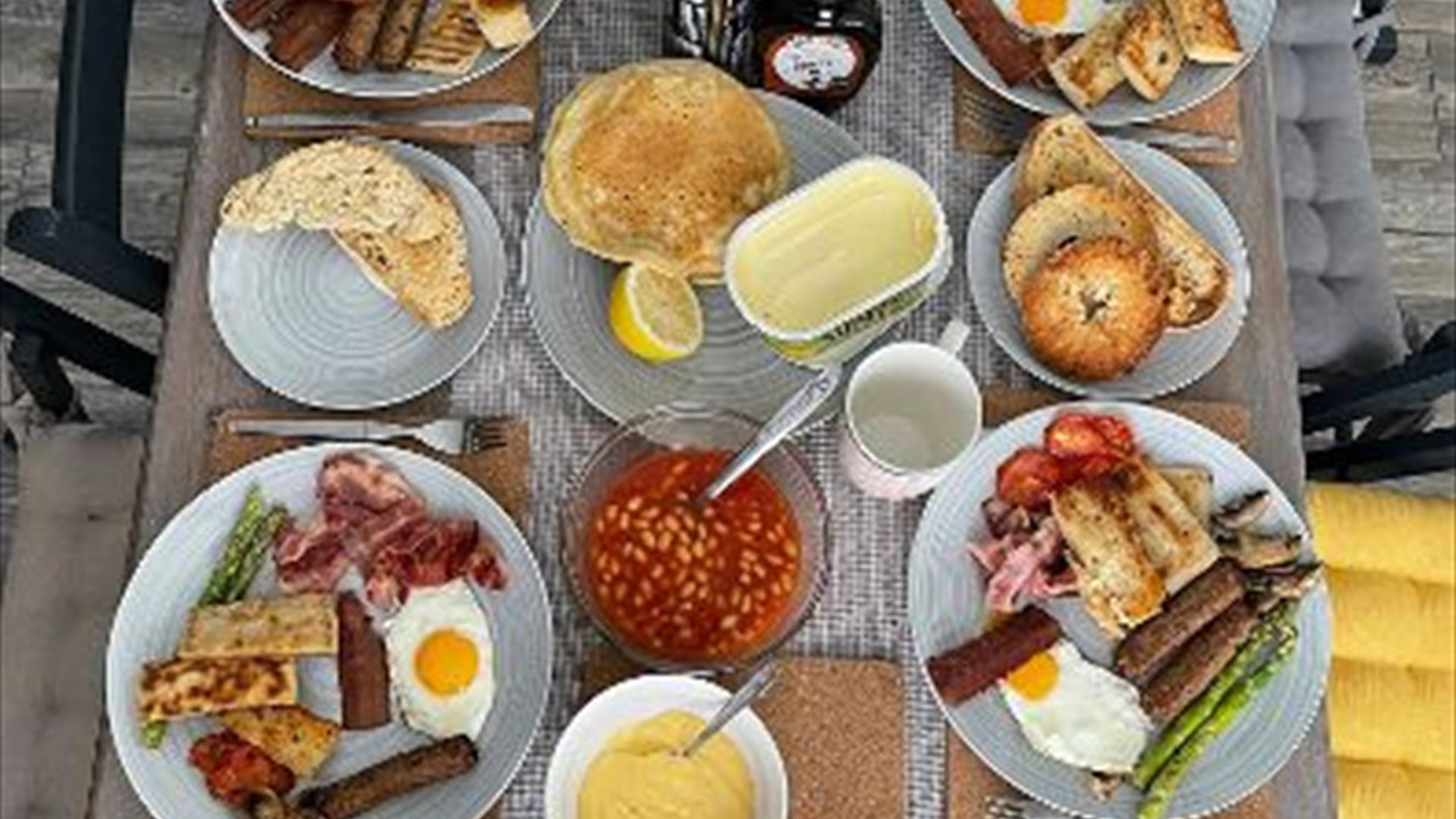 A table set with four places showing cooked breakfasts and other brunch items