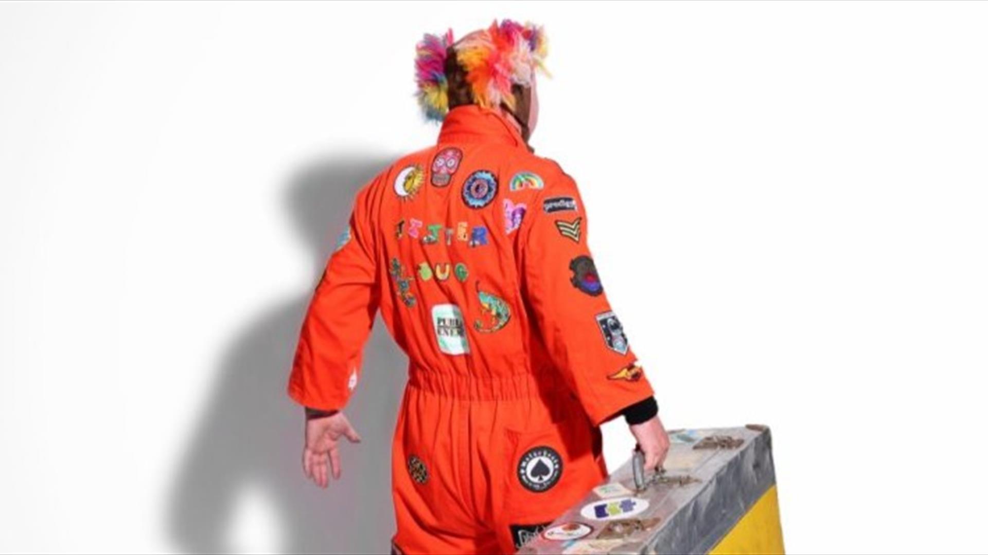 a picture of jitterbug jackson wearing a brightly coloured jumpsuit, facing away from the camera