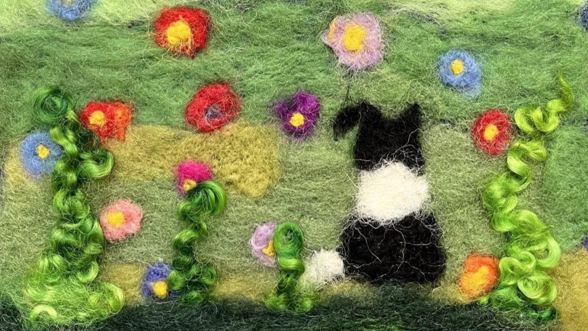 a felted piece with a dog in a field of flowers