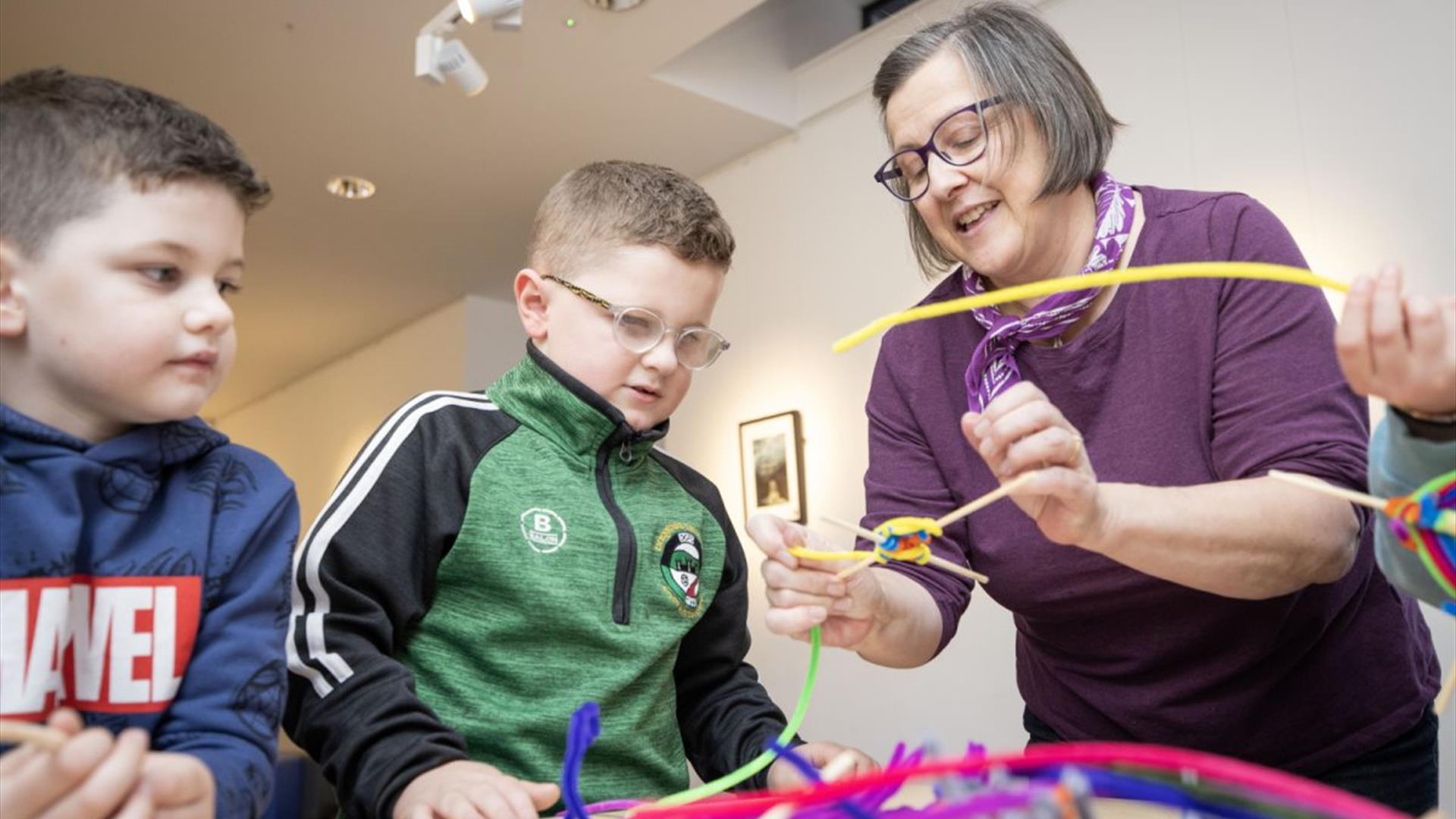 A tutor working with children to make arts and crafts projects
