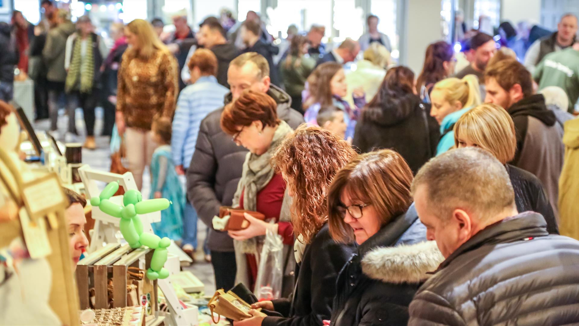 people browsing busy market stalls indoors